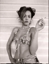 Rita Ora wearing patterned bralette and denim shorts holding a cigarette in black and white editorial photography