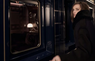 Model Josephine Le Tutour wearing a dark winter coat beside a train window for Madame Figaro Orient Express editorial