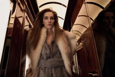 Model Josephine Le Tutour wearing a fur stole and textured coat inside a train cabin for Madame Figaro ORIENT EXPRESS project.