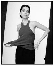 Portrait of a woman wearing a ribbed halter top and dark skirt against a stark studio background for Vogue Thailand.