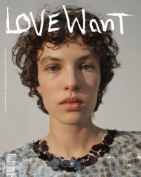 Close-up portrait of a model with short curly hair wearing a sequined top against a plain light background