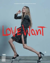 Liisa Winkler in a black and white striped skirt suit and platform heels against a plain grey studio backdrop.