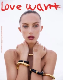 Close-up portrait of a model with sleek hair wearing gold and black sculptural bracelets against a white background
