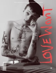 Shirtless young man with extensive tattoos wearing a cap and holding his hand to his head against a plain background