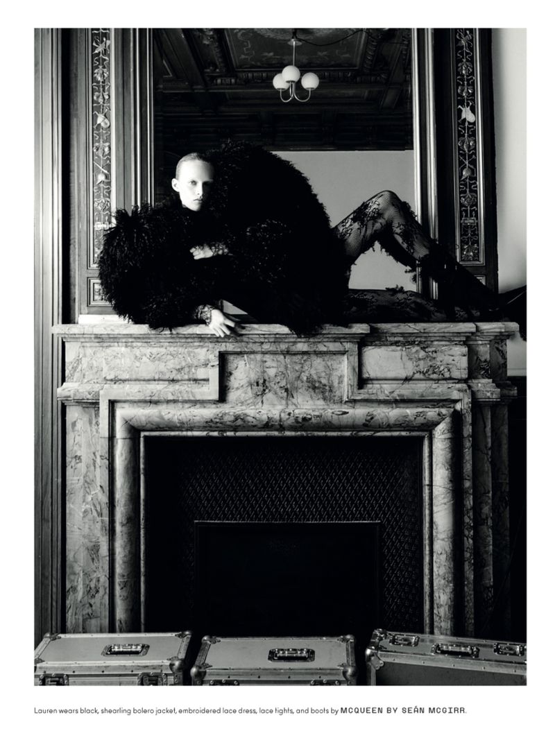 Fashion shot of a person in a black, shaggy bolero jacket and lace tights lying on a marble fireplace mantelpiece with aluminum cases.