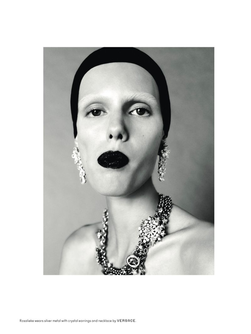 Striking black-and-white beauty shot of a woman with black lipstick, large crystal jewelry, a headband, and fair skin in a studio.