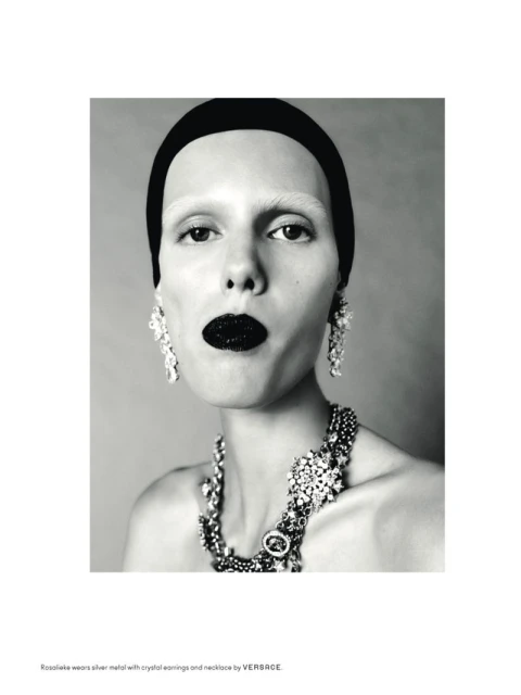 Striking black-and-white beauty shot of a woman with black lipstick, large crystal jewelry, a headband, and fair skin in a studio.