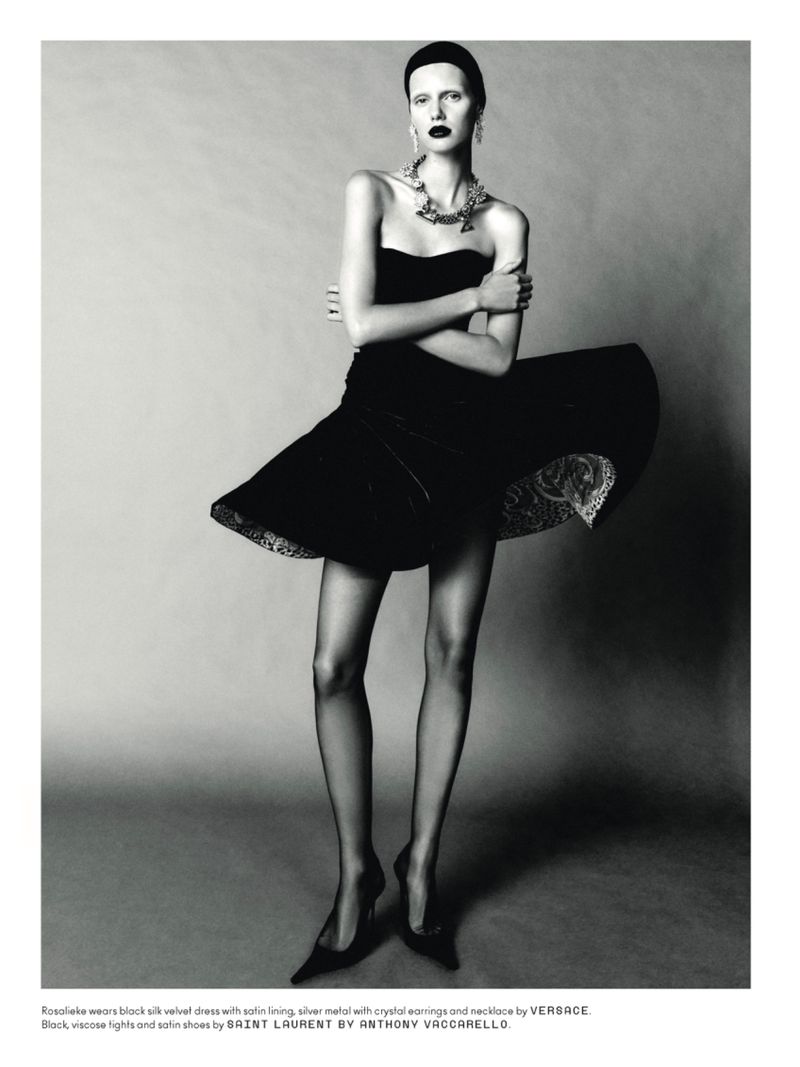 Model in black strapless velvet dress with flared skirt standing against a neutral studio backdrop