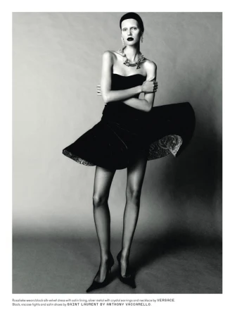 Model in black strapless velvet dress with flared skirt standing against a neutral studio backdrop