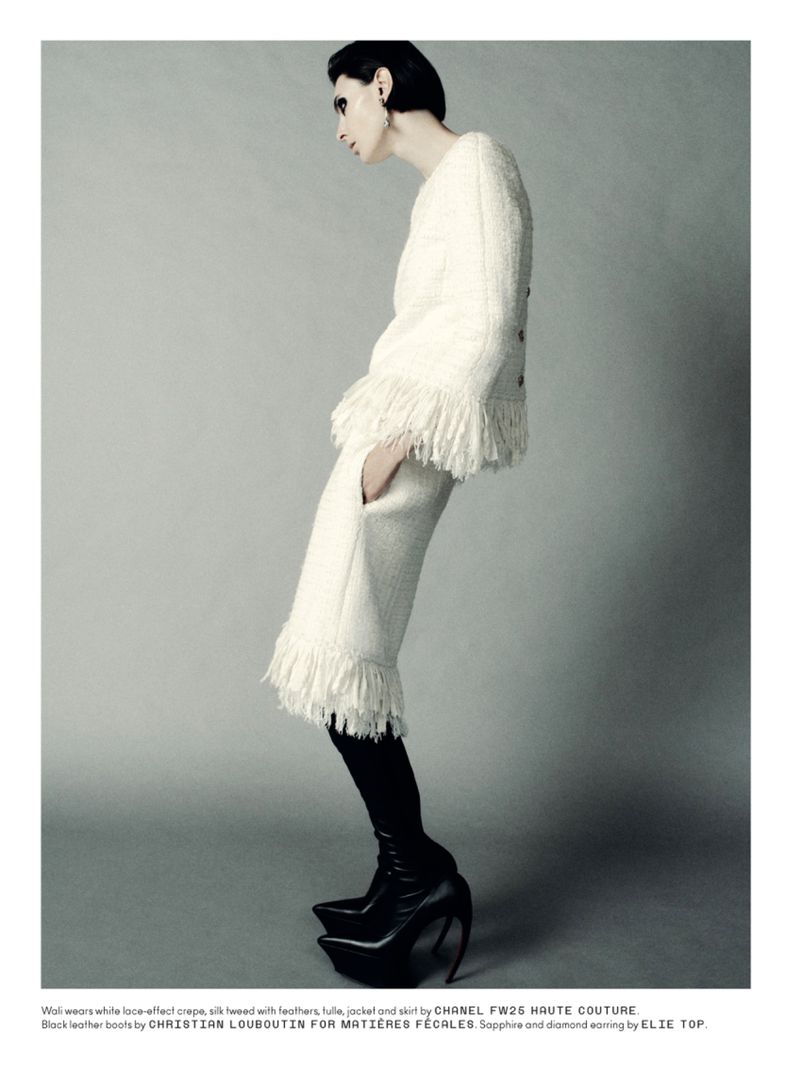 A woman poses in a cream-colored jacket with fringe and matching pants, plus black platform boots against a neutral background.