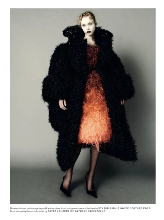 Fashion editorial shot of a woman wearing a degradé feather dress with a large black furry coat and black high heel shoes in studio.