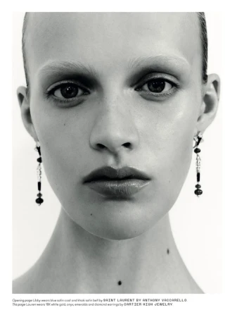 Extreme close-up portrait of a female model wearing long dangling earrings against a plain white background.