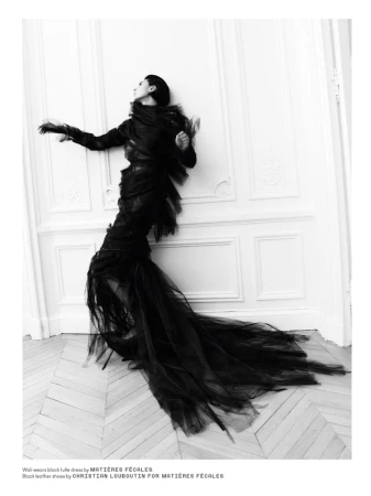 Model in black tulle dress leaning against a white panelled wall by photographer Robin Galiegue for Beyond Noise.
