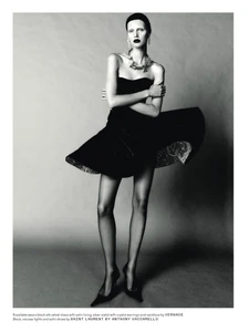 Model in black strapless velvet dress with flared skirt standing against a neutral studio backdrop