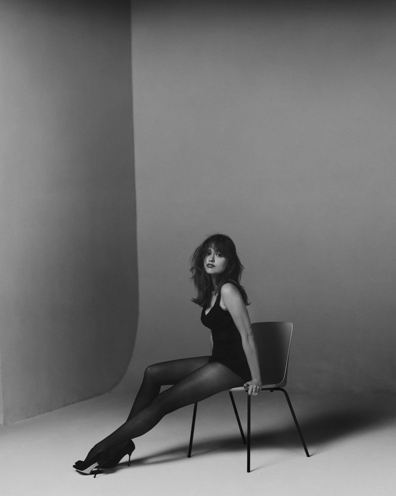 Aimee Lou Wood seated on a chair in a studio setting for Harper's Bazaar UK.