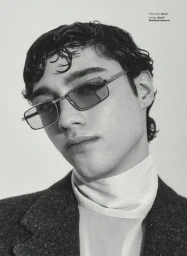 Close-up portrait of a young man wearing tinted rectangular sunglasses and a dark textured blazer for GQ Mexico.