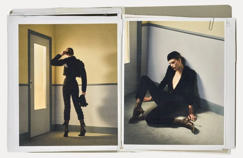 Two fashion photographs show a woman in a suit by a door and a man in a suit sitting on the floor in coordinated artistic poses.