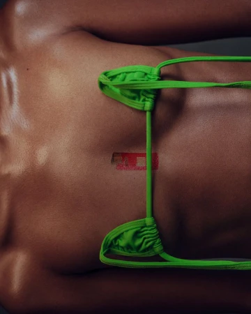 Torso of a man with shiny skin and an adhesive bandage. A neon green thong is placed on the body.