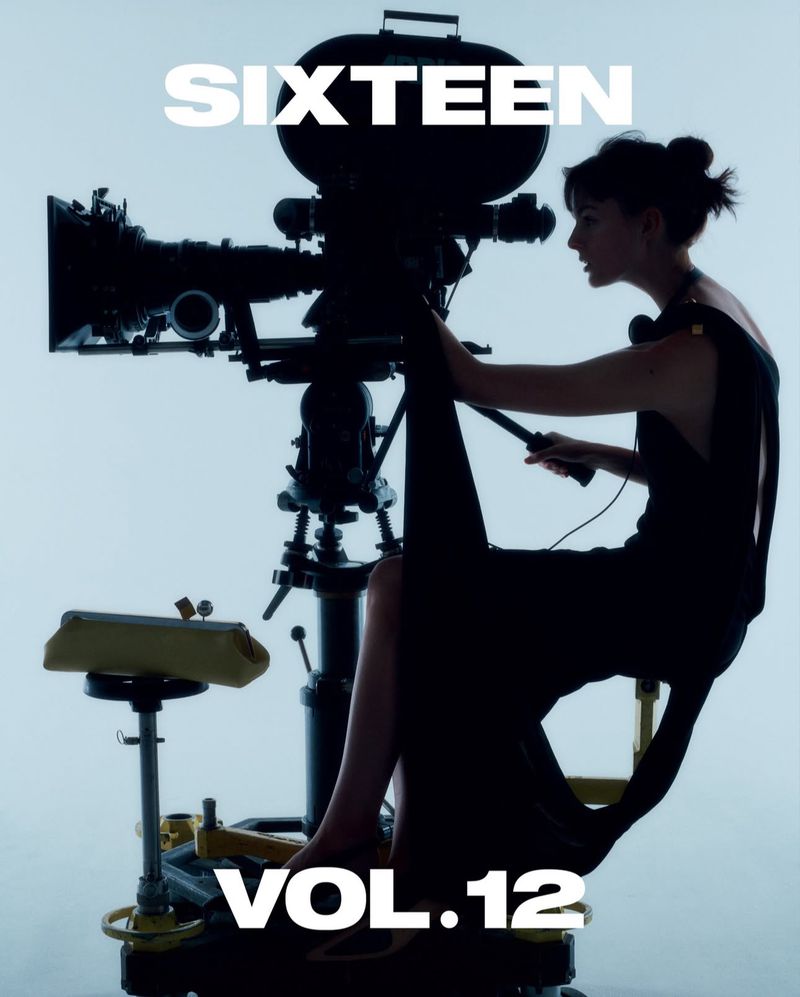 Woman in black dress operates vintage camera against soft white background. Focus on camera and operator in photo studio setting.