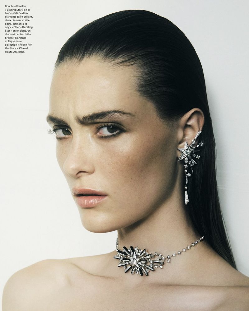 Close-up shot of a model wearing a starburst-style choker and star-shaped ear cuff jewelry in a studio setting against a white backdrop.
