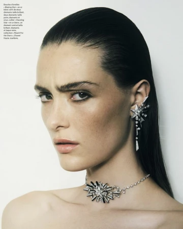 Close-up portrait of a model with slicked-back dark hair wearing diamond star earrings and a statement choker necklace