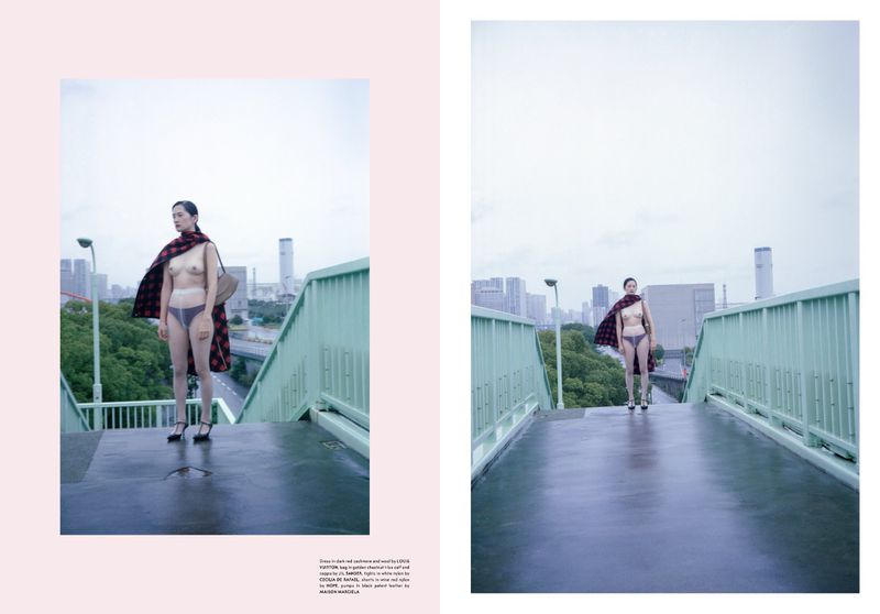 Fashion editorial shot on an urban bridge shows a slender adult female in minimal undergarments and draped with a tartan shawl.