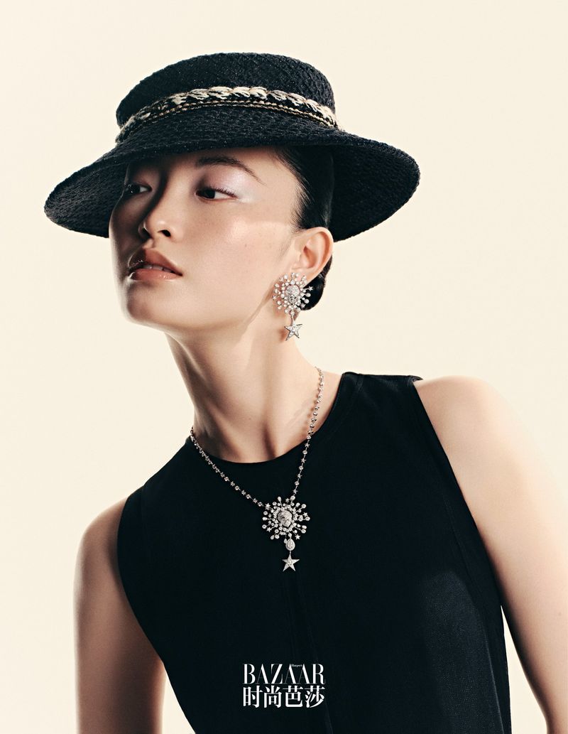 Model wearing a black hat, statement diamond earrings, and a matching necklace against a light background for Harper's Bazaar China.