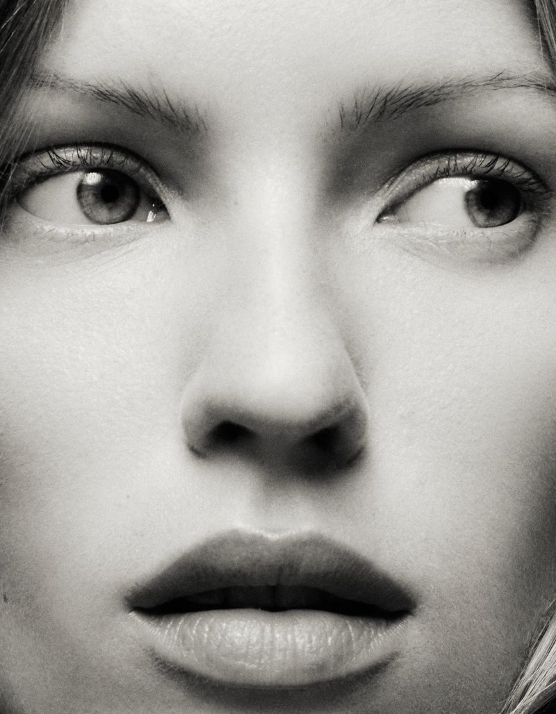 Close-up portrait of an adult woman with blonde hair, looking sideways with a neutral expression in a black and white photo.