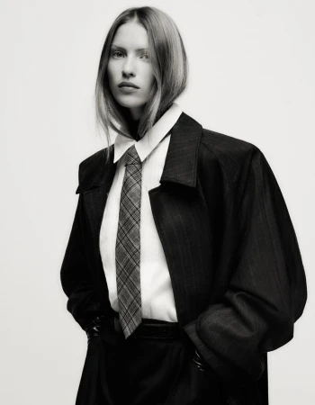 Model Lea Seelenmeyer in a black coat, white shirt, and patterned tie against a plain backdrop for Yo Dona Spain.