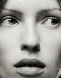 Extreme close-up monochrome portrait of a female model looking sideways with soft lighting and natural skin texture.