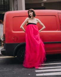 Model Hannah Vincent in a strapless hot pink tulle gown posing against a red van on an urban street.