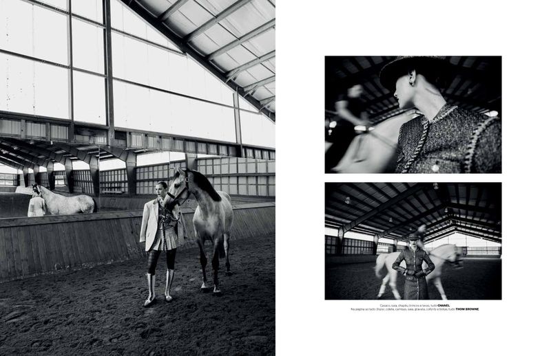 Black and white fashion shot in an indoor riding arena featuring a person and a horse standing on a dirt floor.