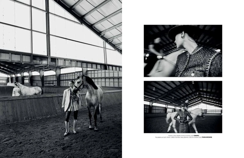 Black and white fashion shot in an indoor riding arena featuring a person and a horse standing on a dirt floor.