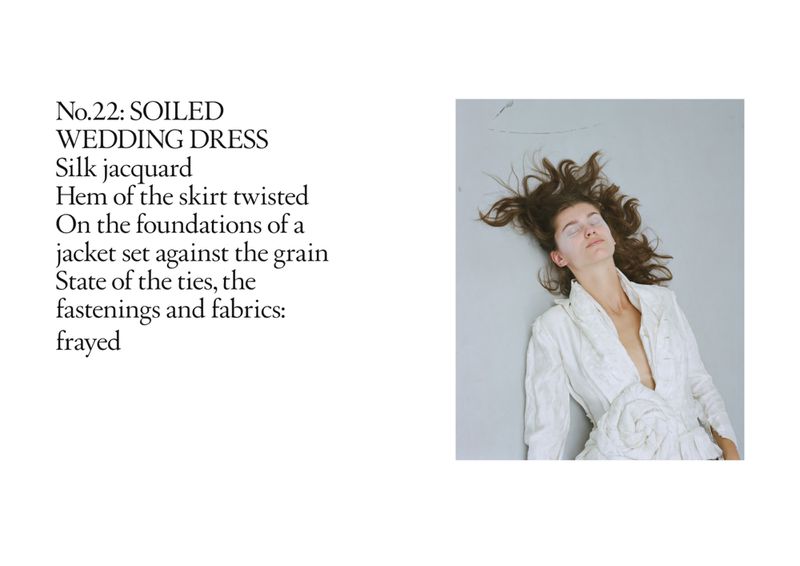 Woman lying on a gray surface wearing a white dress, with her dark hair spread out around her head, shot in a portrait format.