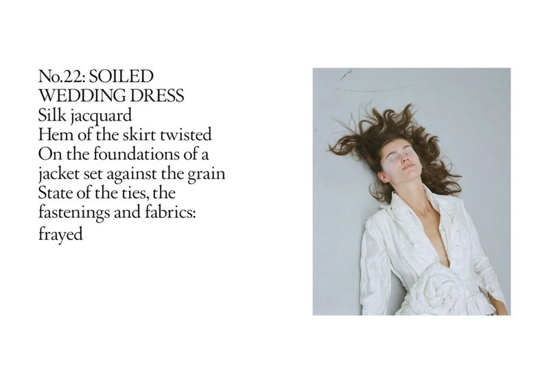 Woman lying on a gray surface wearing a white dress, with her dark hair spread out around her head, shot in a portrait format.