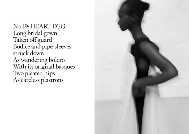 Monochrome fashion portrait of a Black model in a gown with flowing fabric, set against a simple white wall with poem text.