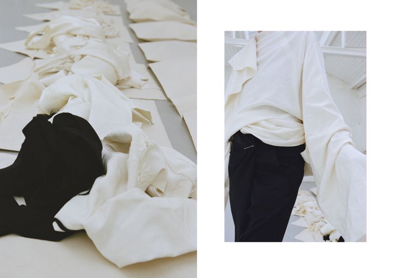Fashion layout featuring a person in a white top and black pants, styled with various fabric pieces on the floor in a studio setting.