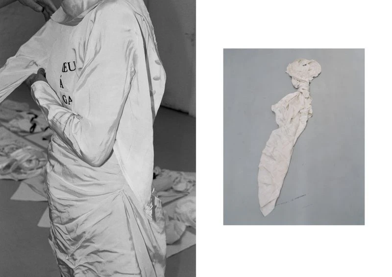 Fashion photography featuring a model being dressed in a white dress with text, accompanied by a crumbled dress on a gray background.