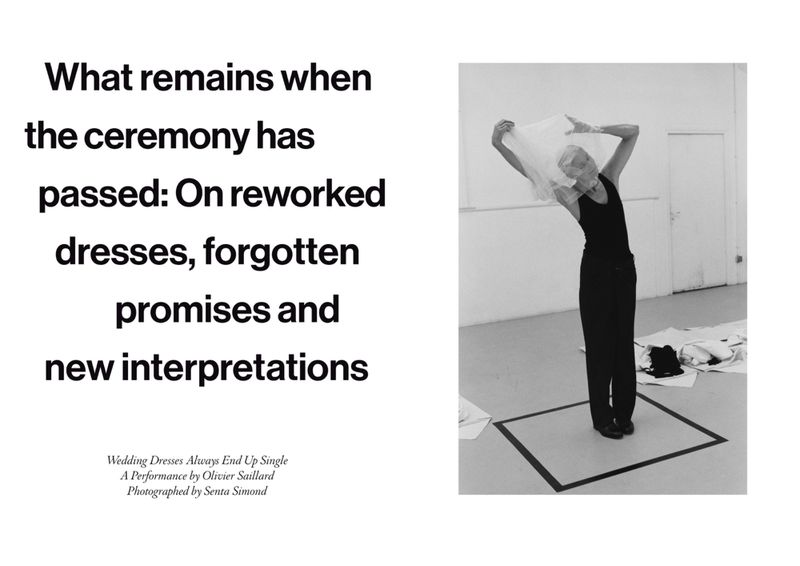 Black and white photograph of an adult female posing with fabric inside a square frame drawn on the floor in a white, minimalist space.