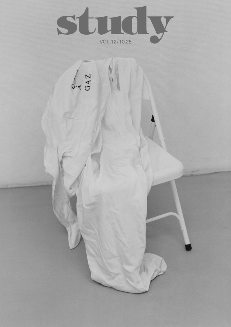 A white lab coat hangs on a metal folding chair in a stark white and gray setting with the word 'study' visible above.