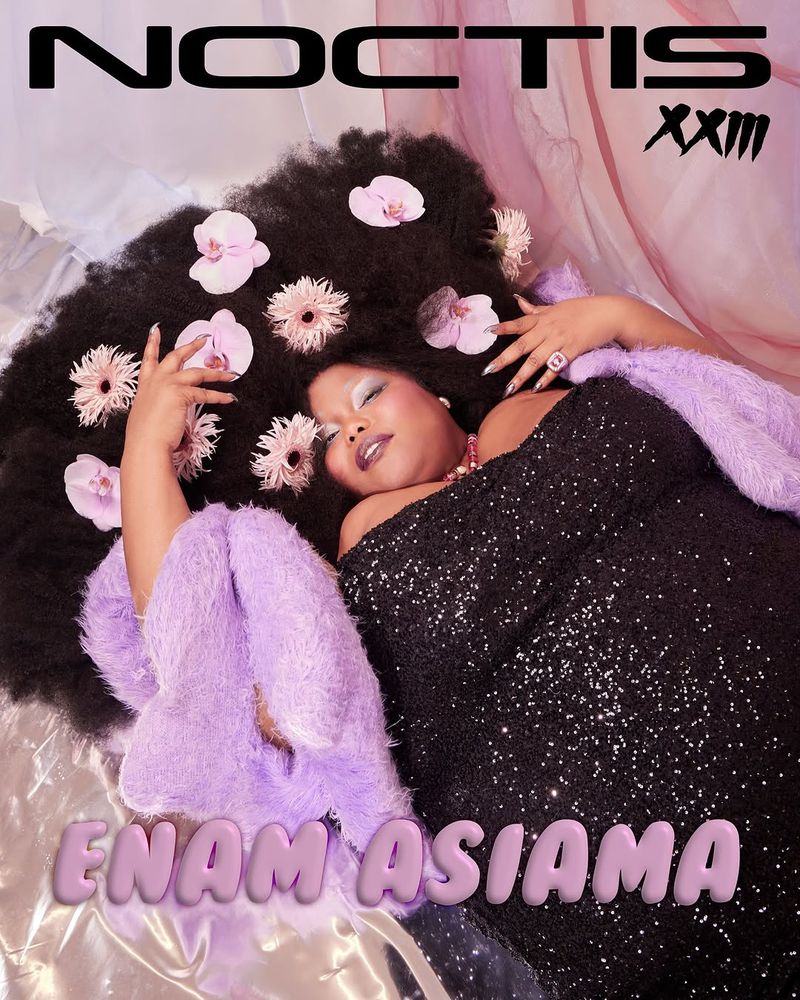Woman in black dress with flowers in her hair lies on silvery fabric. A lilac fur stole and text overlays add to the stylish fashion shot.