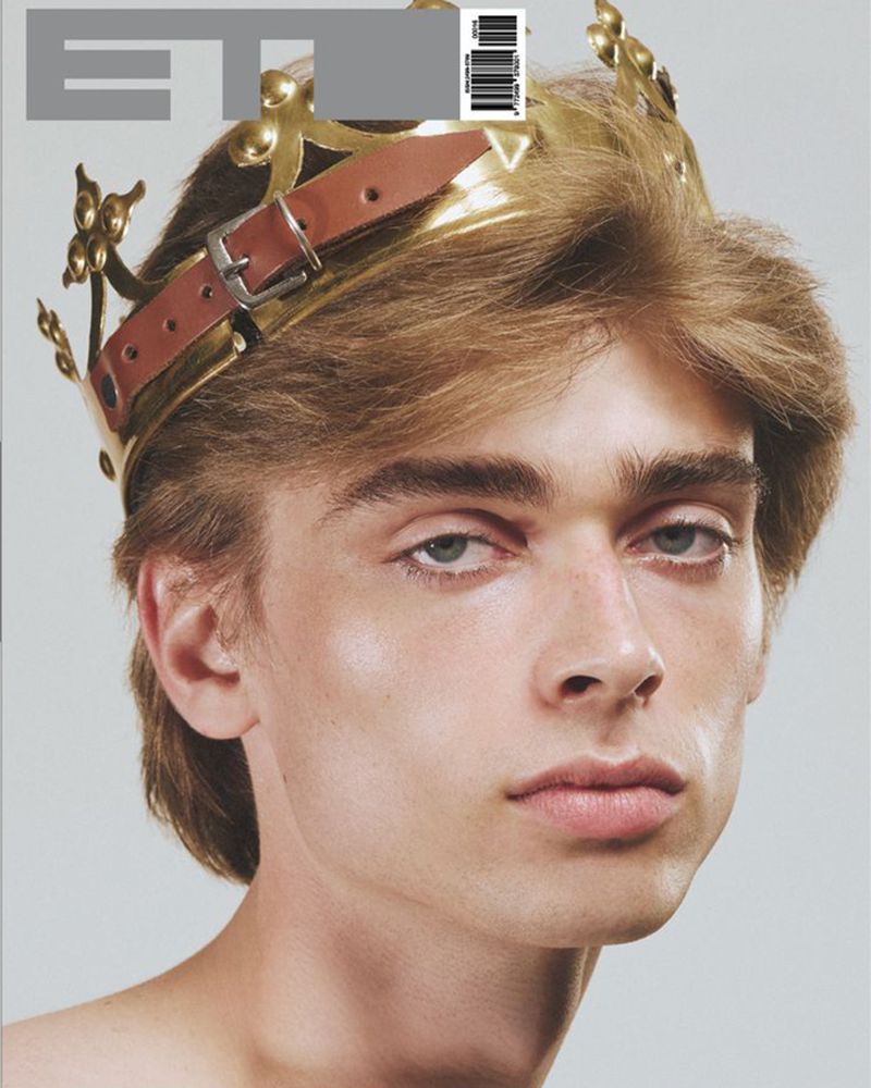 Magazine cover featuring a young male model with blond hair wearing a decorative golden crown with a leather strap detail.