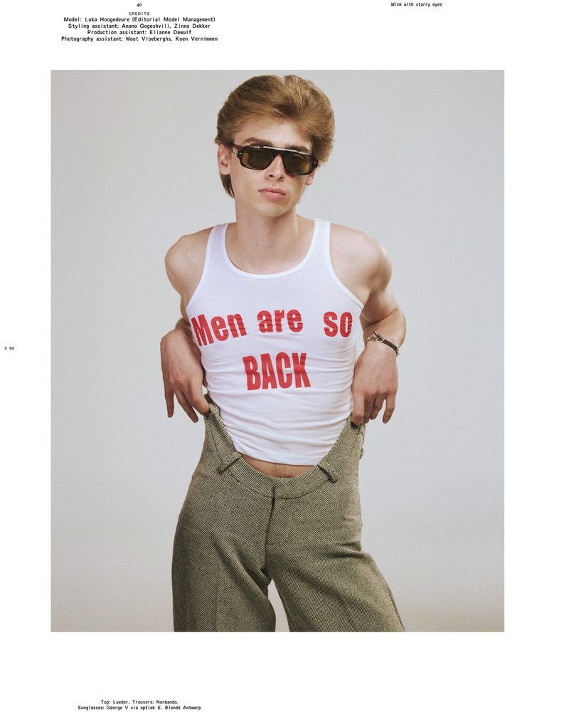 Model Luka Hoogedeure wearing dark sunglasses, a white graphic tank top, and high-waisted olive trousers against a studio background.