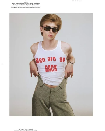 Model Luka Hoogedeure wearing dark sunglasses, a white graphic tank top, and high-waisted olive trousers against a studio background.