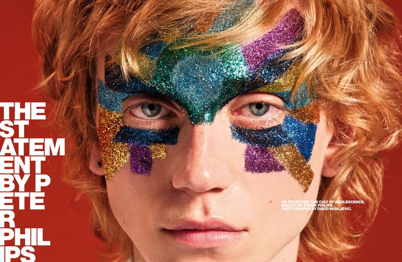 Beauty shot of a person with glitter makeup in blue, gold, purple, and green, posing against a red background with visible text.
