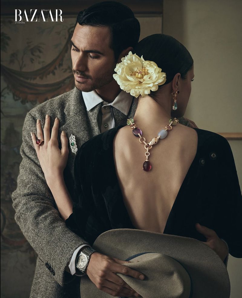 Fashion editorial featuring a stylish couple. The man is wearing a tweed jacket, and the woman is wearing a black dress with a necklace.