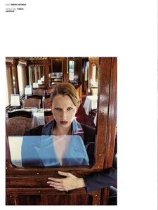 Model Linda Novotna looking through a wooden train window wearing a blue collar top and dark jacket inside a vintage carriage.
