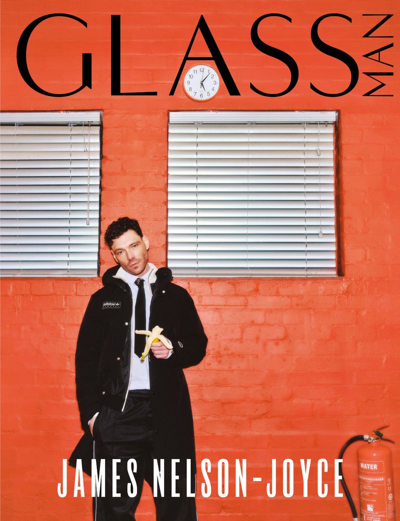 Magazine cover featuring James Nelson-Joyce in a black coat holding a banana, with red brick wall, white blinds, and "GLASS MAN" text.