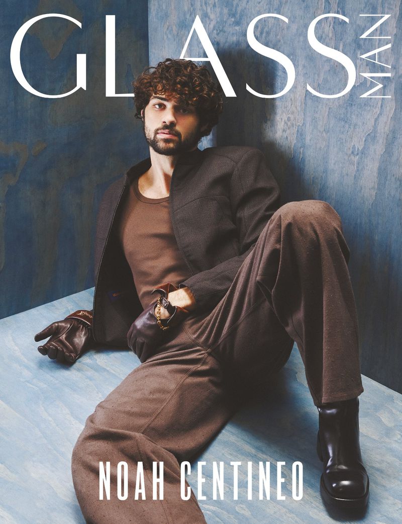 Glass Man magazine cover featuring Noah Centineo seated in earth-tone outfit against a textured blue wall backdrop.