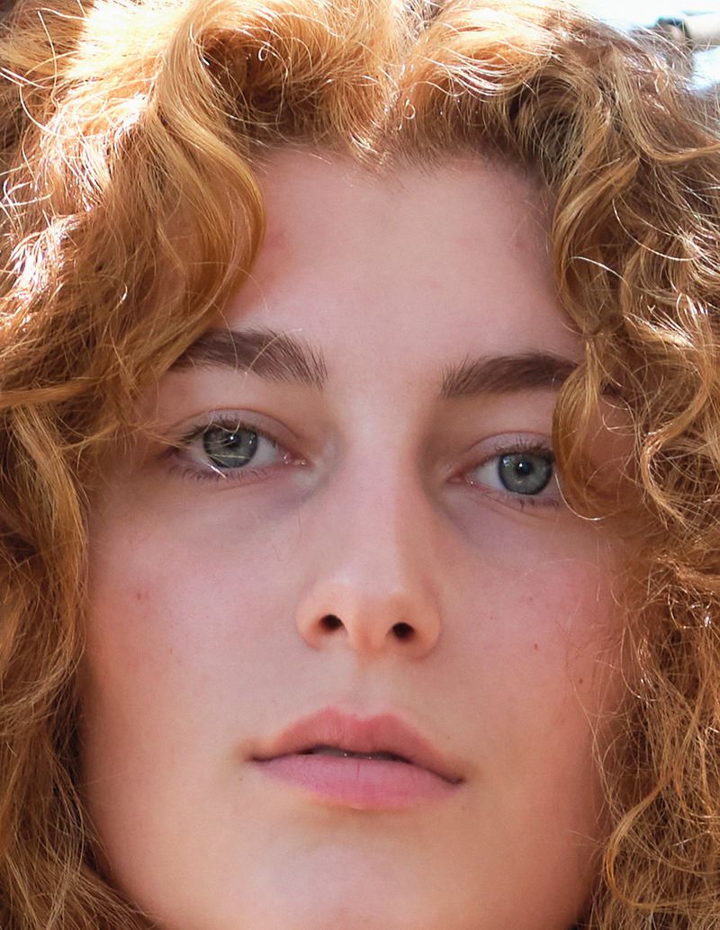Close-up portrait of a woman with curly red hair and light eyes for Double Magazine Agapi Mou editorial